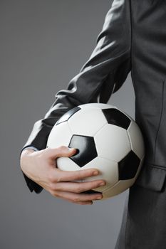 Elegant businessman holding a soccer ball, close up