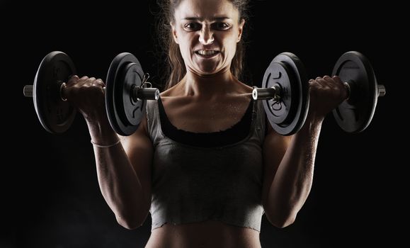 Young woman lifting the dumbbells