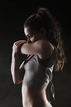 Young woman stretching on black background