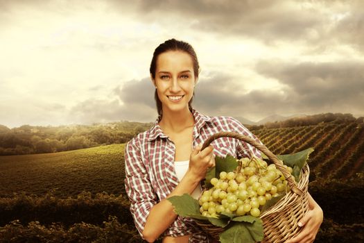 Smiling woman with basket of grapes in the vineyard