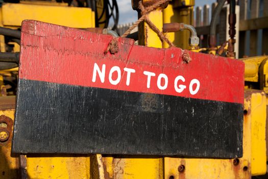 A wooden sign painted red and black with the words 'NOT TO GO' painted in white.