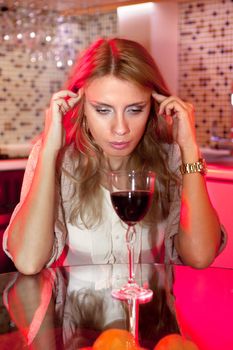 sad beautiful woman in kitchen with glass of wine