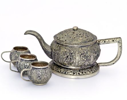 Antique tea pot and cups made ​​of metal, isolated on a white background.