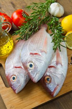 a group of sea bream with lemon and rosemary on wood table