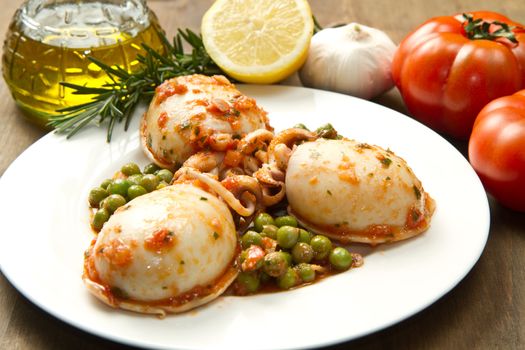 a white bowl with cuttlefish with peas and fresh tomatoes, lemon and oil