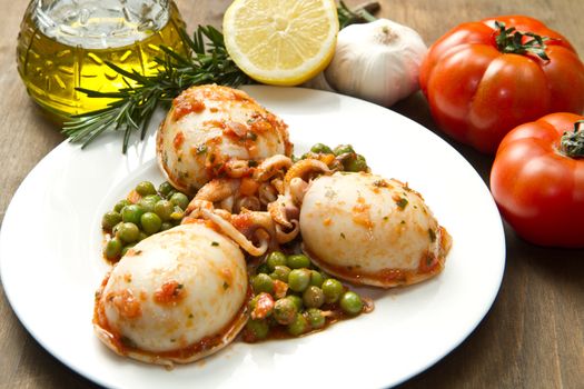 a white bowl with cuttlefish with peas and fresh tomatoes, lemon and oil