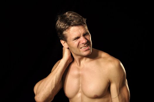 Muscular shirtless male athlete suffers from neck pain