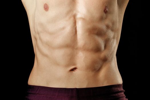 Closeup of athletic man's abs on black background