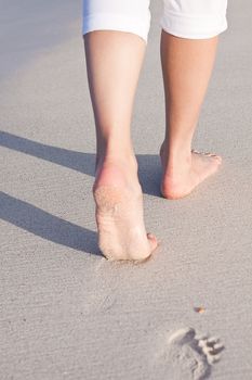 walking barefoot in the sand in summer holidays on beach