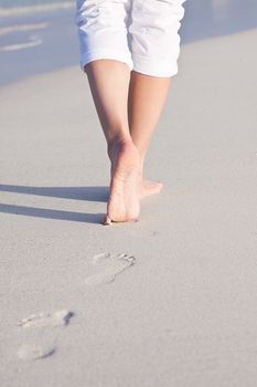 walking barefoot in the sand in summer holidays on beach