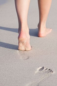 walking barefoot in the sand in summer holidays on beach
