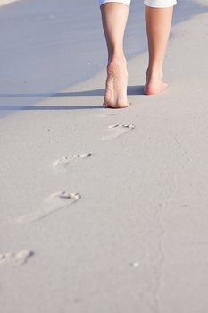 walking barefoot in the sand in summer holidays on beach