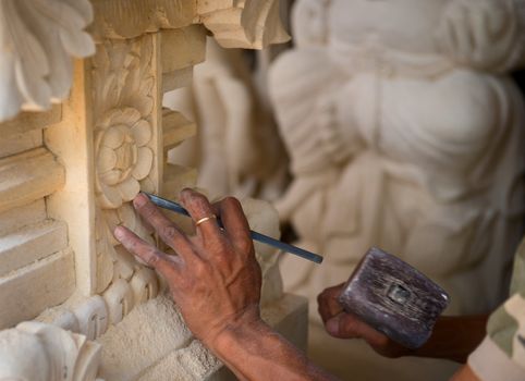 Stone mason at work carving an ornamental relief 