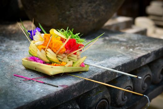 Traditional balinese offerings to gods in Bali with flowers and aromatic sticks