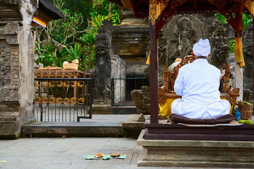 Balinese unrecognizable priest dressed in white clothes in Hindu temple during a religious ceremony, Bali, Indonesia