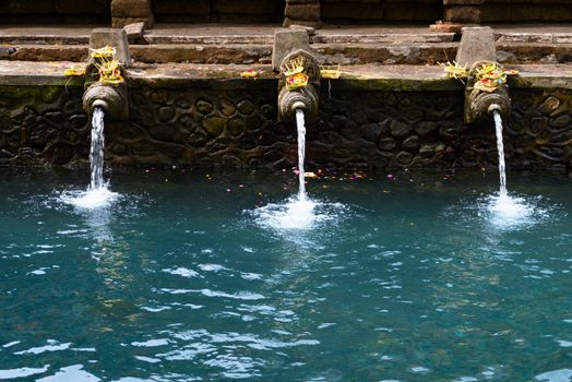 Fountains and pool with holy spring water in Tirta Empul temple, Bali, Indonesia 