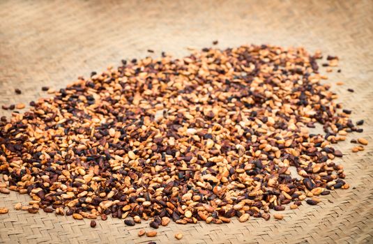 Pile of raw unpeeled cacao beans on mat with shallow depth of field