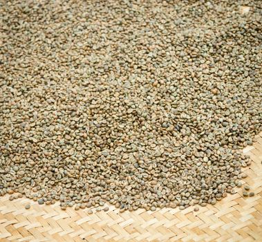 Green unroasted coffee beans on mat with shallow depth of field