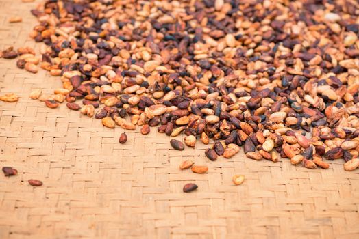 Pile of raw unpeeled cacao beans on mat with shallow depth of field
