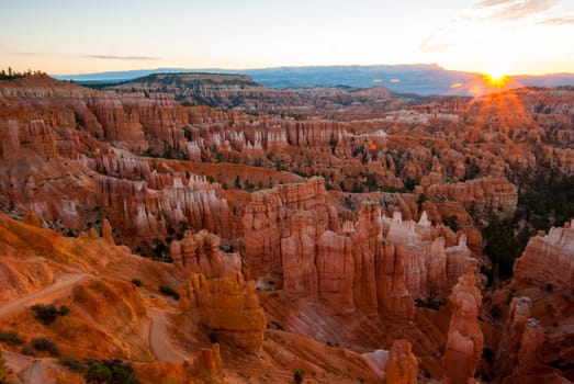 Photograph of the Bryce Amphitheater from overlook taken at sunrise showing geologic formations and Hoodoos.