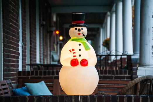 Photograph of a Lighted Christmas Snowman Decoration on the front porch of a row home in Baltimore City.