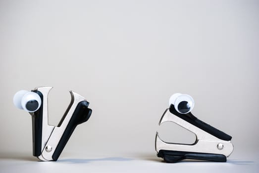 Photograph of staple removers with oogly eyes on a white background.