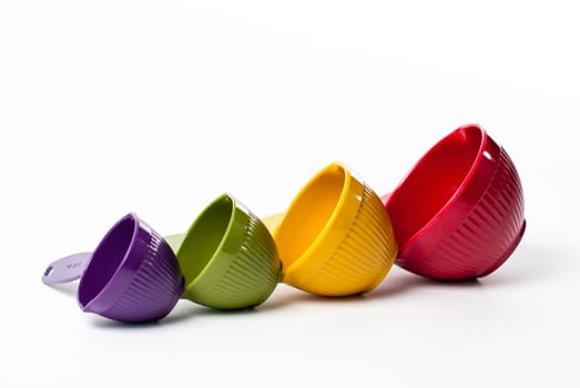 Photograph of a set of 4 colorful measuring cups of increasing size on a white background.