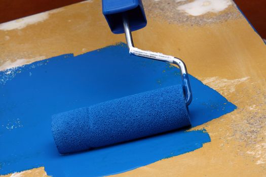 Roller brush with blue paint close up 