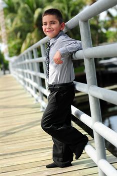 
Cute young boy leanings against pole on bridge outdoors