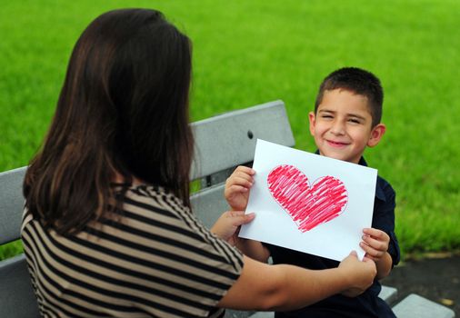 young boy giving his mother a heart drawing for a present