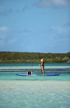 young woman fishing on paddle board in tropical scenic ocean waters