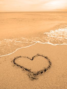 A warm tropical beach with waves and a heart drawn in the sand