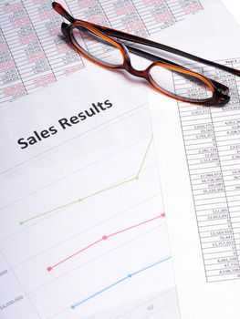 Business Charts and graphs showing sales results with a pair of glasses