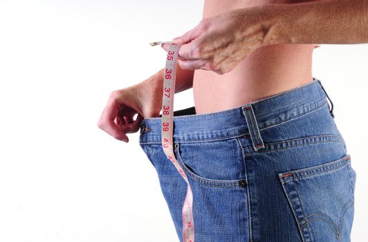 healthy young woman with measuring tape and loose jeans demonstrating weight loss