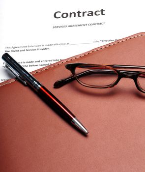 A business contract with reading glasses and a pen