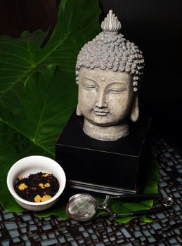 Black tea leaves with Buddha statue and tea infuser or strainer