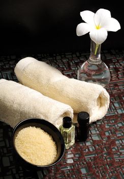 Essential oils, bath salts, towels and a frangipani flower