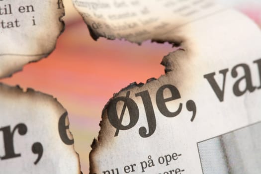 burnt newspaper (in danish) and colorful background