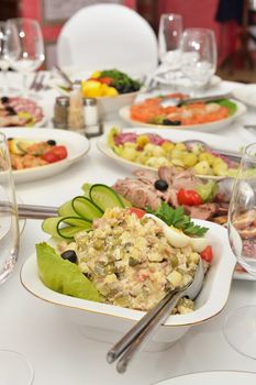 Salad on the served table. Snacks, wine glasses and restaurant serving.