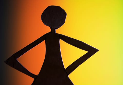 woman silhouette cut in small rudimentary figures  in paper , shot with colorfull background