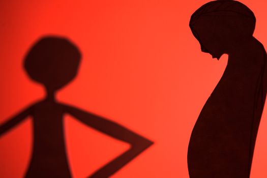 man and woman silhouette cut in small rudimentary figures  in paper , shot with colorfull background