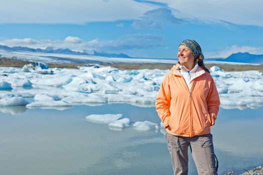 Young woman enjoying the view Jokulsarlon a lake in Iceland where icebergs collapsing from Vatnajokull glacier are floating around.