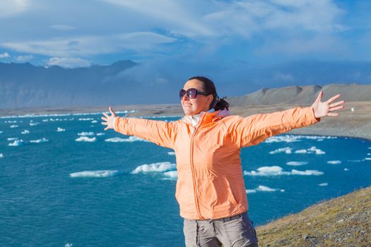Young woman enjoying the view Jokulsarlon a lake in Iceland where icebergs collapsing from Vatnajokull glacier are floating around.
