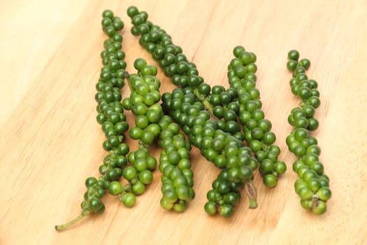 Green peppercorns on a wooden board