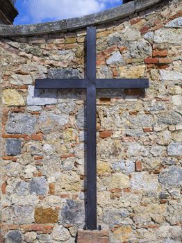 Vertical image of a cross in an old wall seen in Tuscany, Italy