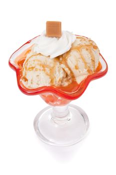 Cup of Caramel ice cream decorated with whipped cream and caramel chunk over a white background