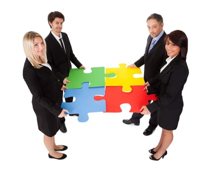 Group of business people assembling jigsaw puzzle. Isolated on white