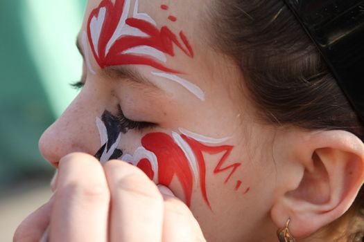 young girl paints face with carnival ornament