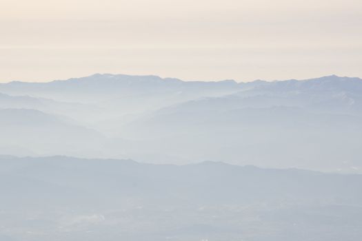 Mountain landscape with fog and sunshine, outline of mountains