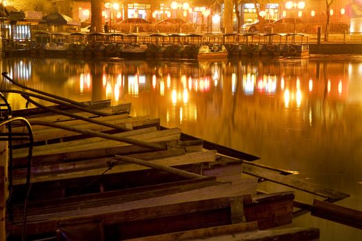 Wooden Boats on Houhai Lake with Lights of Bars and Restaurants in background, Beijing, China.  Hohai is the old swimming hole in the City and is now surrounded by bars and restaurants and is one of the well-known night districts in Beijing.